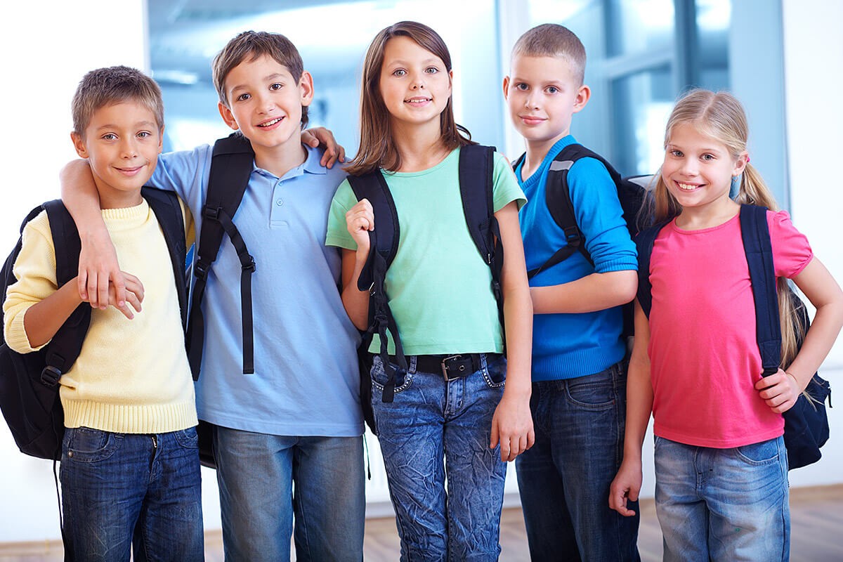 Schoolchildren stand with briefcases