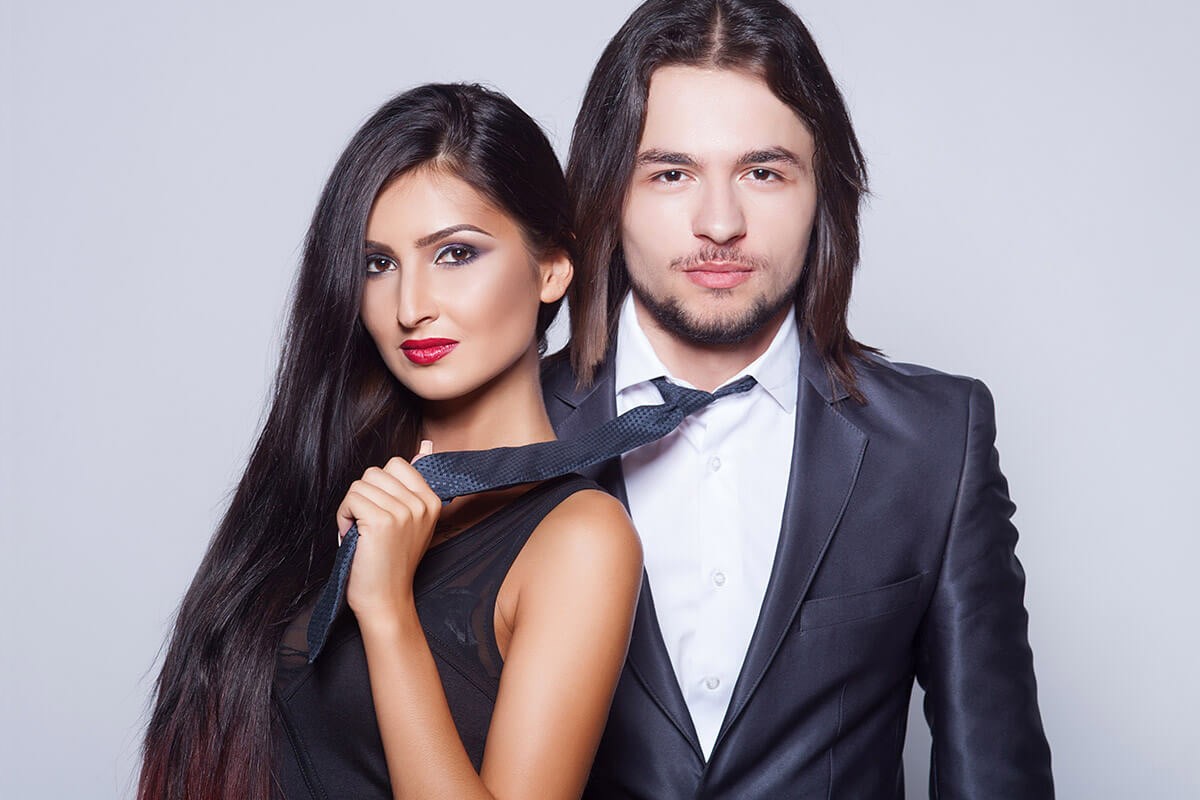 Charming woman leads an attractive guy over a tie