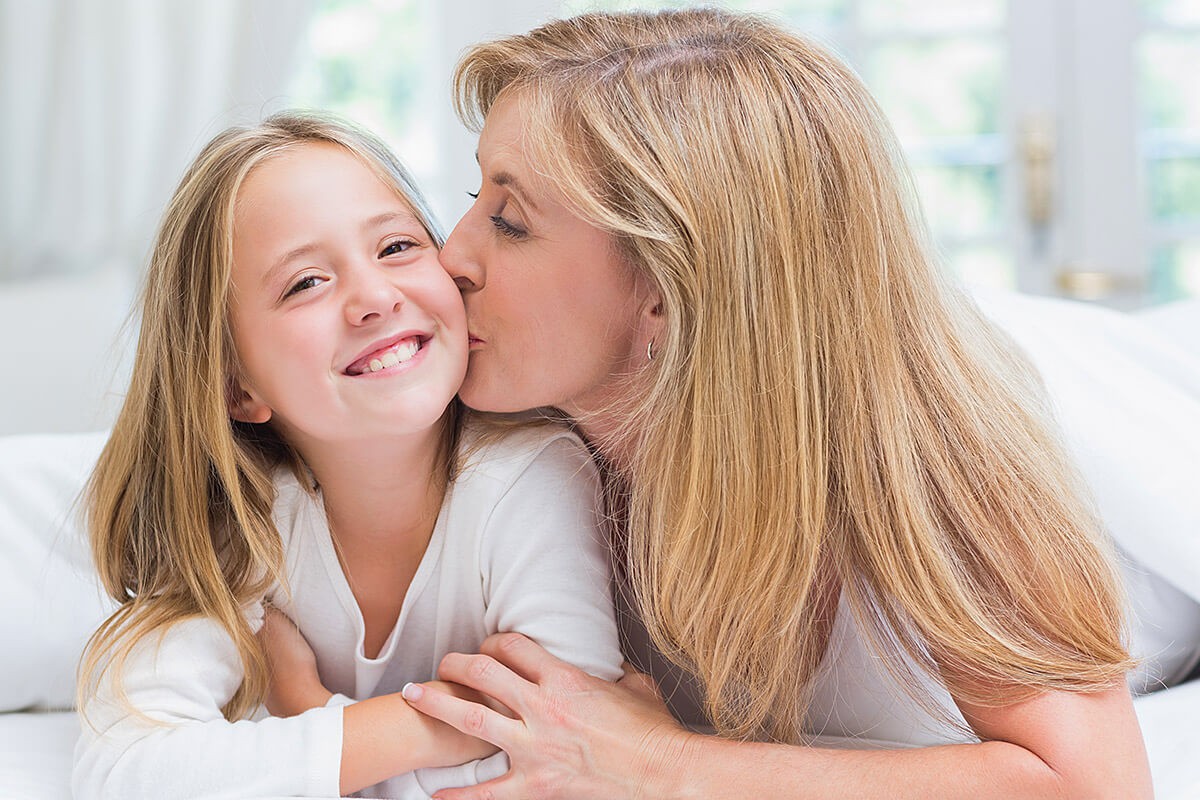 Woman gently kisses her daughter on the cheek