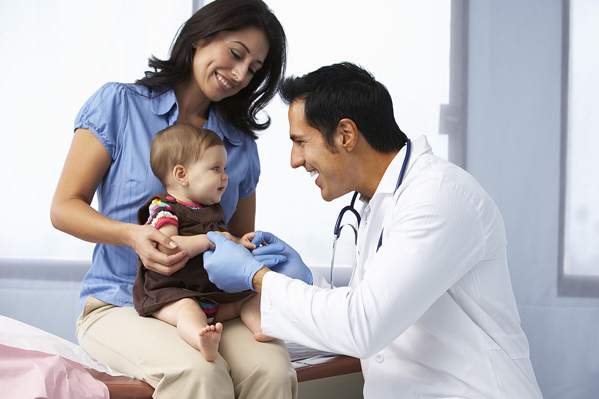Doctor examines a child in her mother’s arms