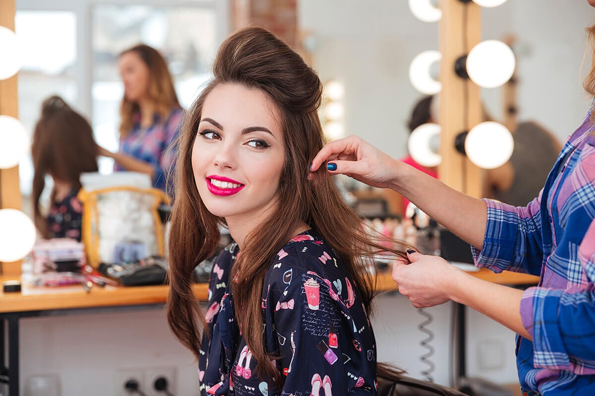 The hairdresser looks at the ends of the hair of a woman