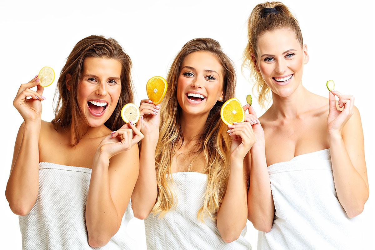Image of well-groomed three girls with fruits in their hands
