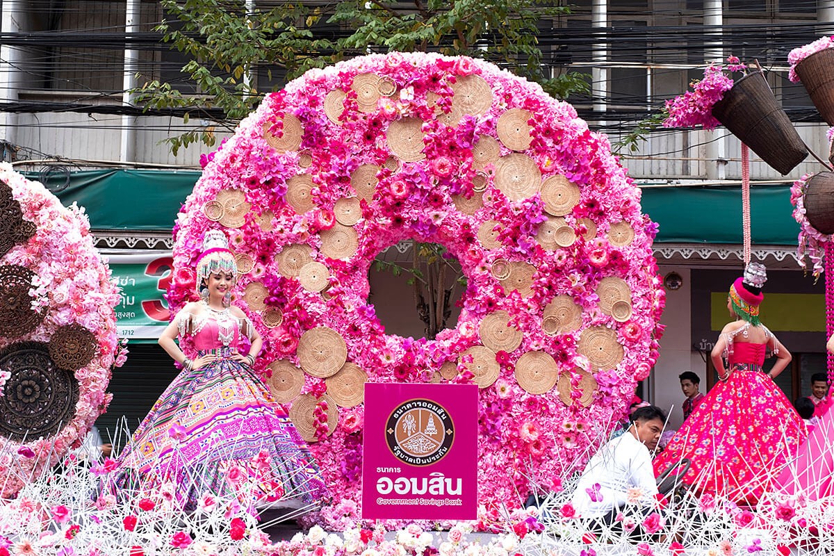 Young women dressed in colorful clothes standing in a colorful flower float at the Flower Festival Parade, Chiang Mai
