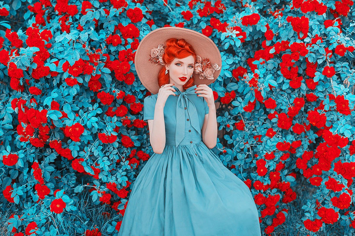 Image of a real lady in a hat and dress on a background of flowers