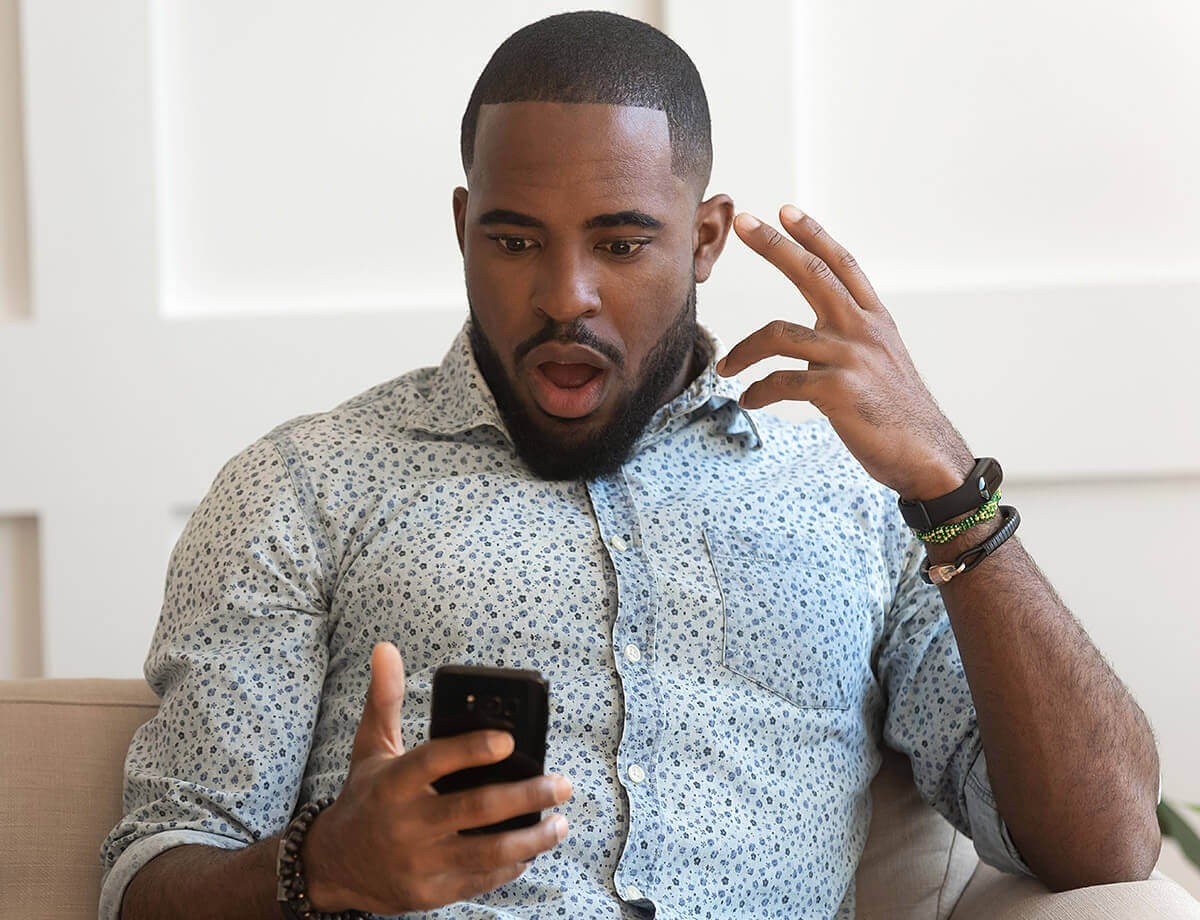 Surprised man looks at the correspondence in the mobile phone of his wife
