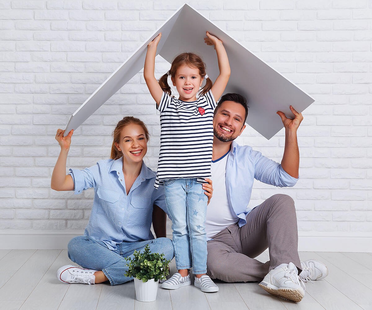 Joyful couple and a child build a house of paper together