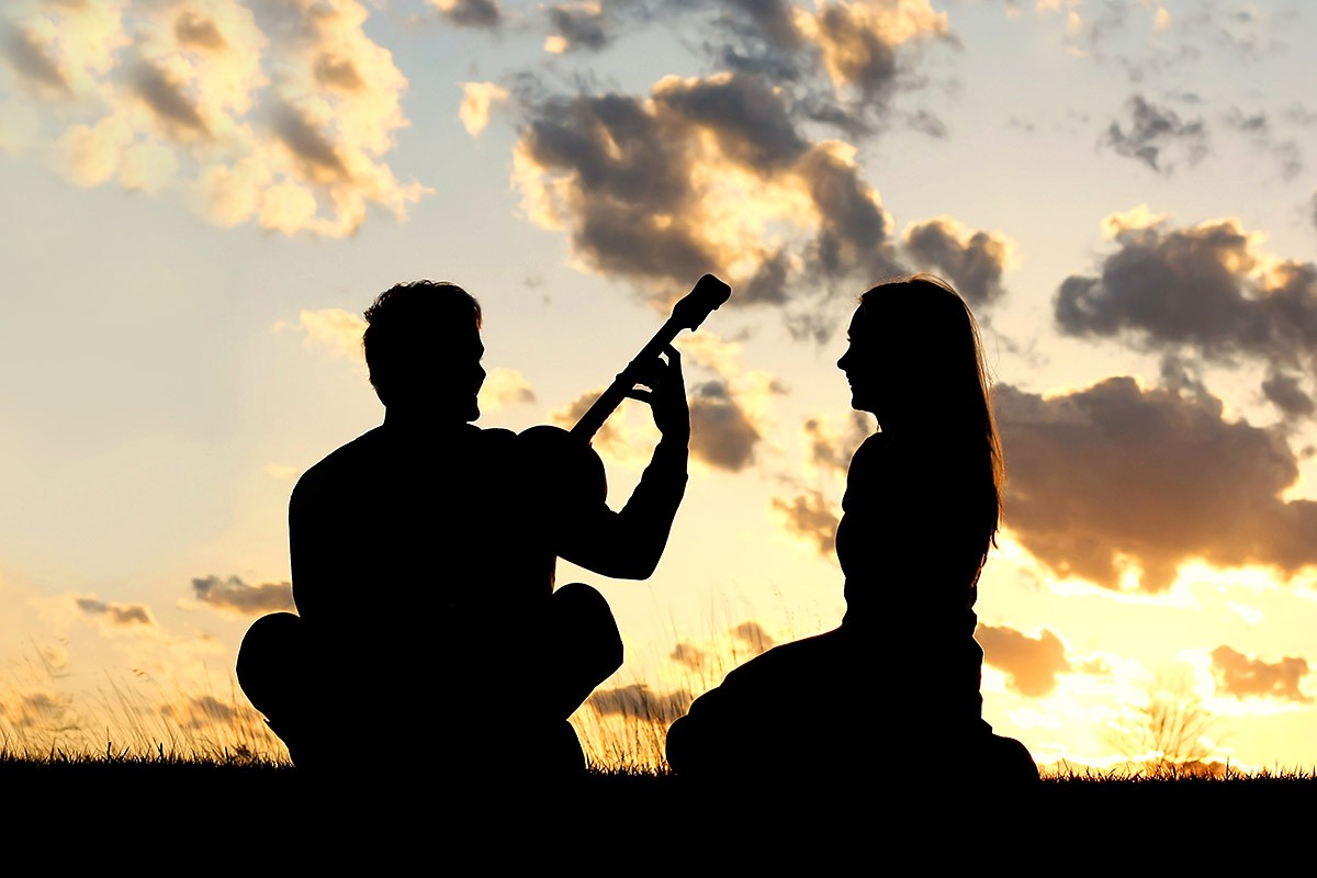 Loving man and woman at sunrise with a guitar