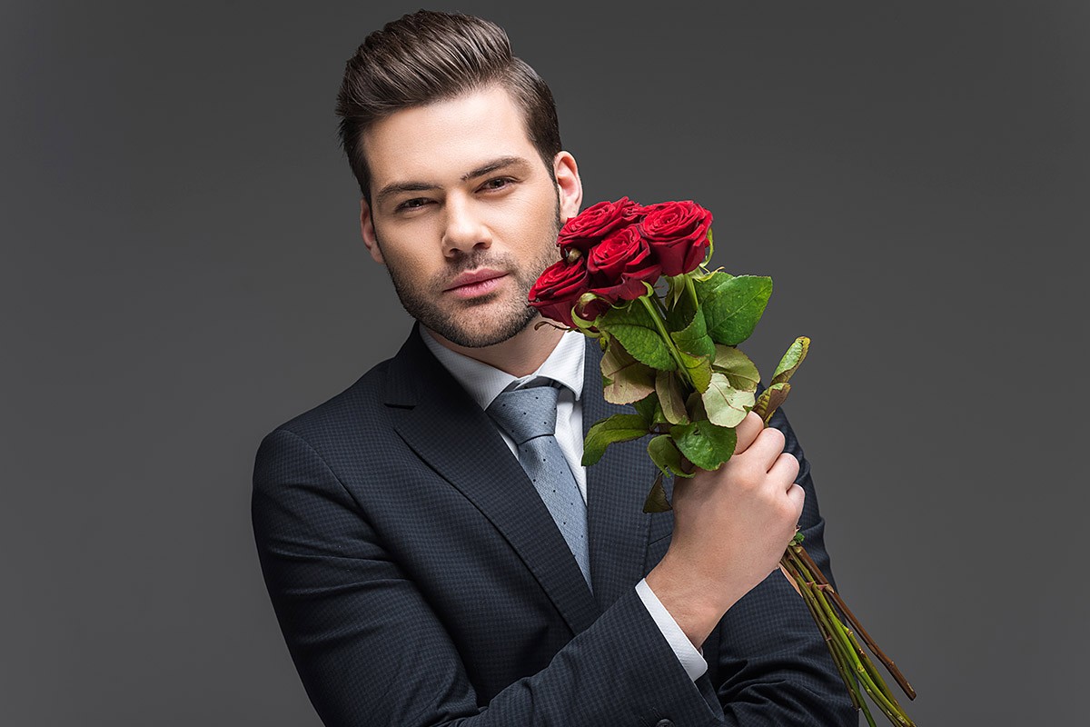 Loving handsome man in a suit and with flowers