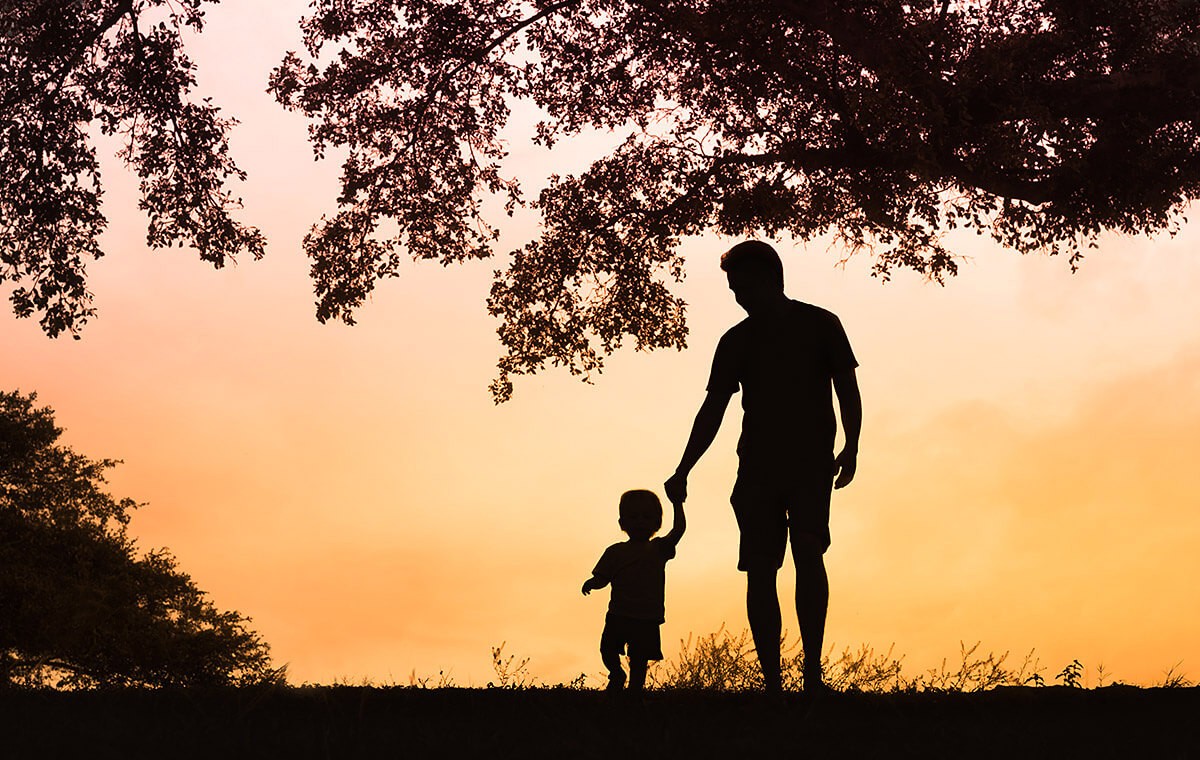 Father walks with his son at sunset