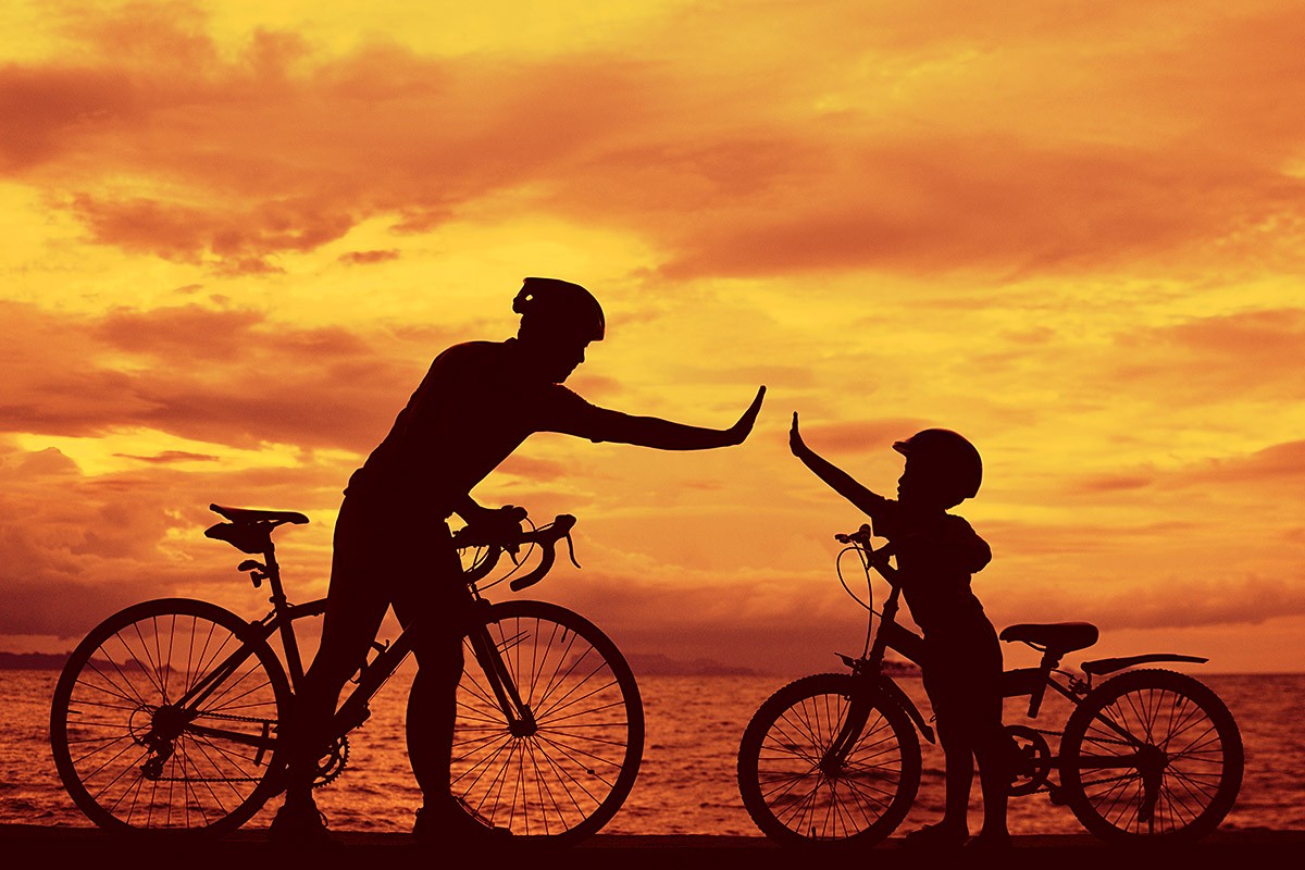 Father and son ride bikes by the sea