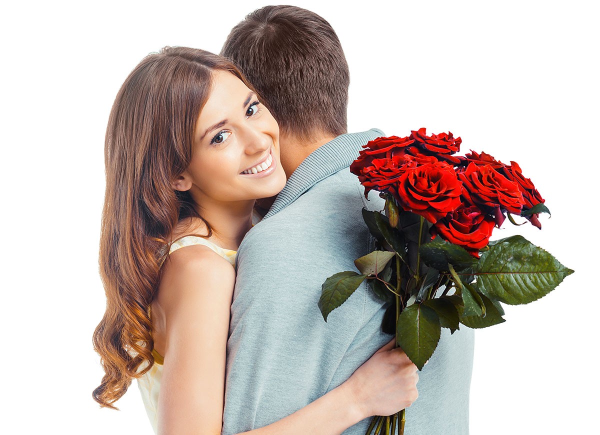 Young man hugging his girlfriend and gives her a bouquet of flowers