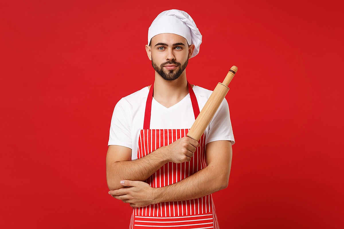 Cute man in a cap and with a rolling pin in his hands
