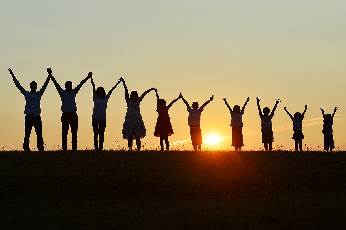 Image of adults and children holding hands at sunset