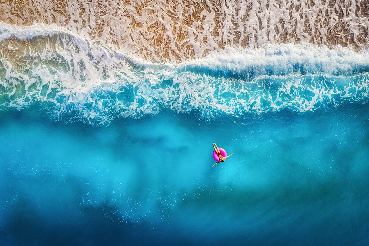 Aerial view of a floating girl in the sea