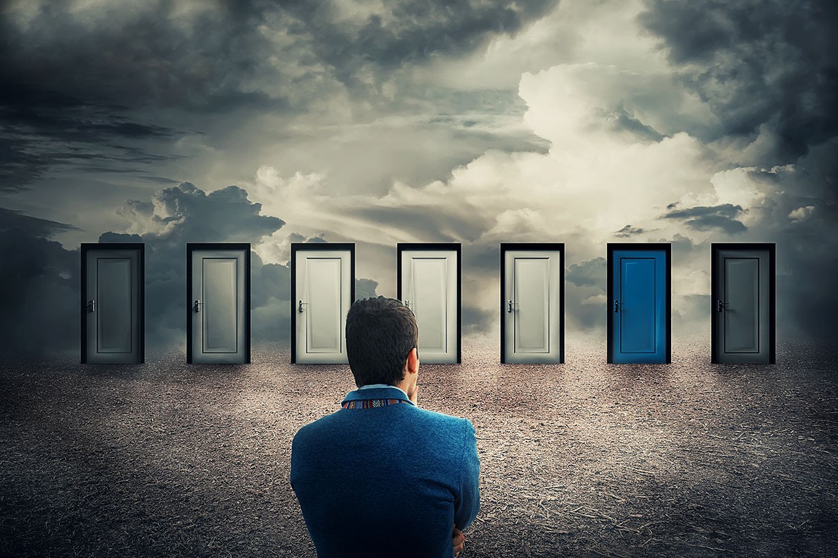 A man stands in front of many doors and decides which one to go to A man stands in front of many doors and decides which one to go to
