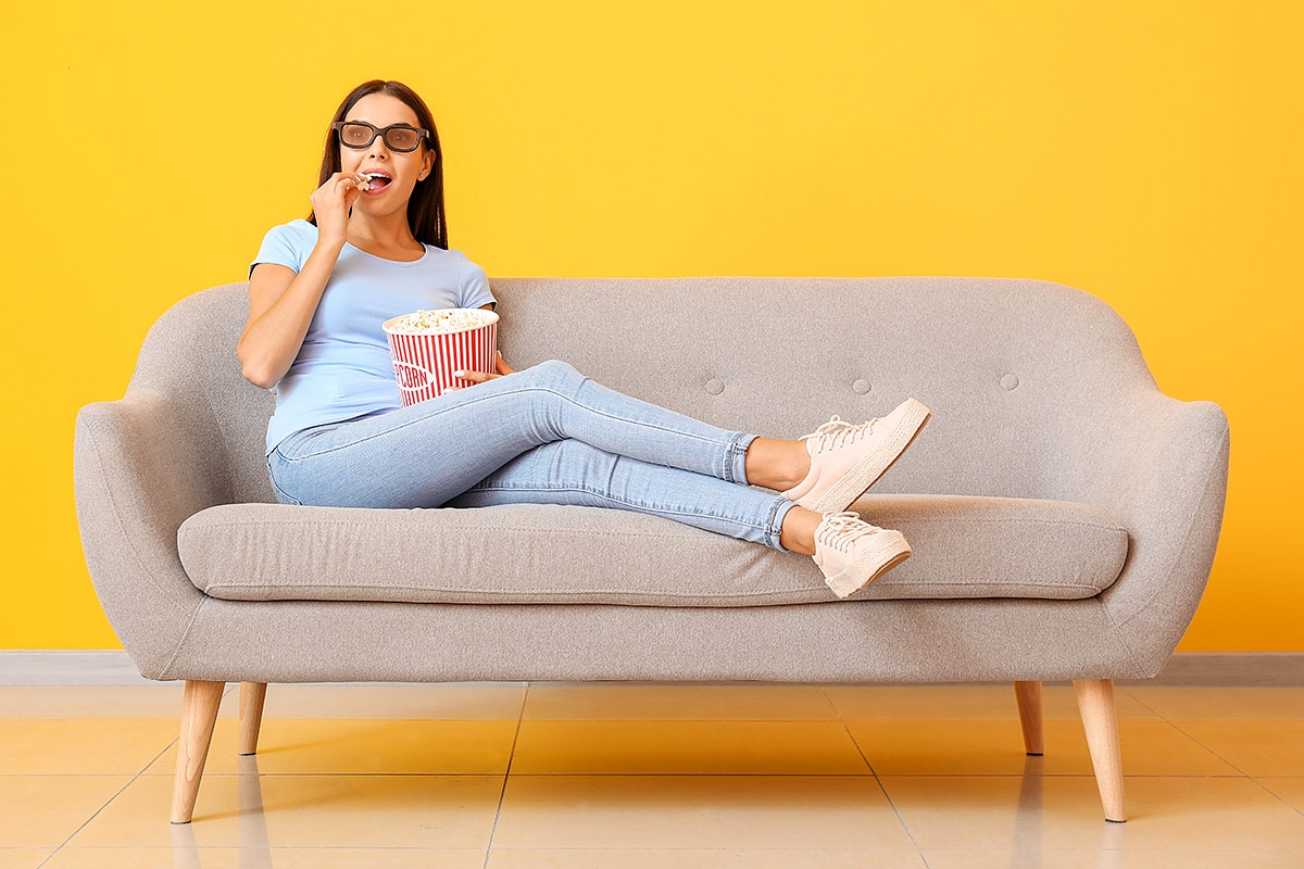 Surprised woman sitting on sofa and eating popcorn Surprised woman sitting on sofa and eating popcorn