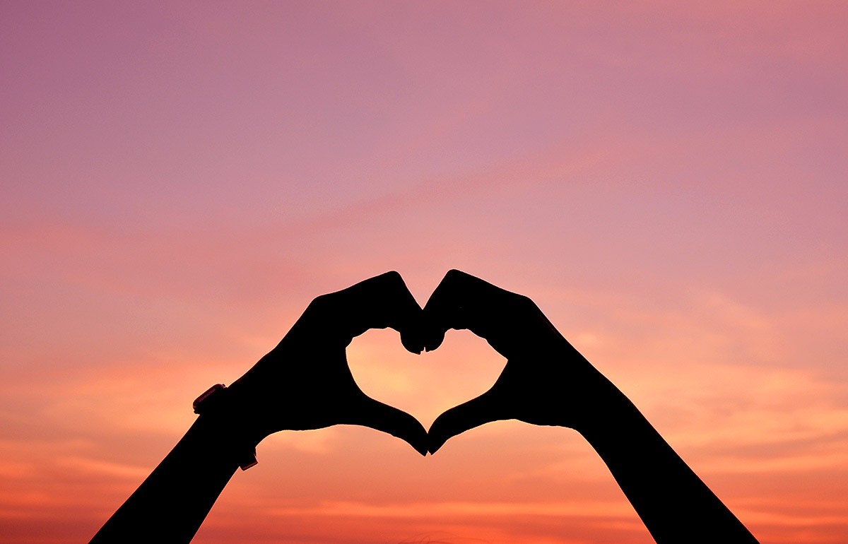 Image of hands in the form of a heart of love at sunset
