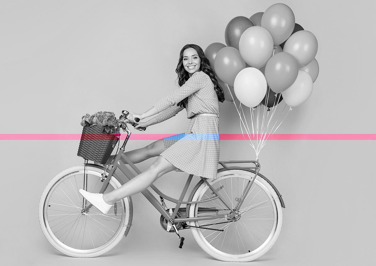 Joyful woman on bike and with balloons