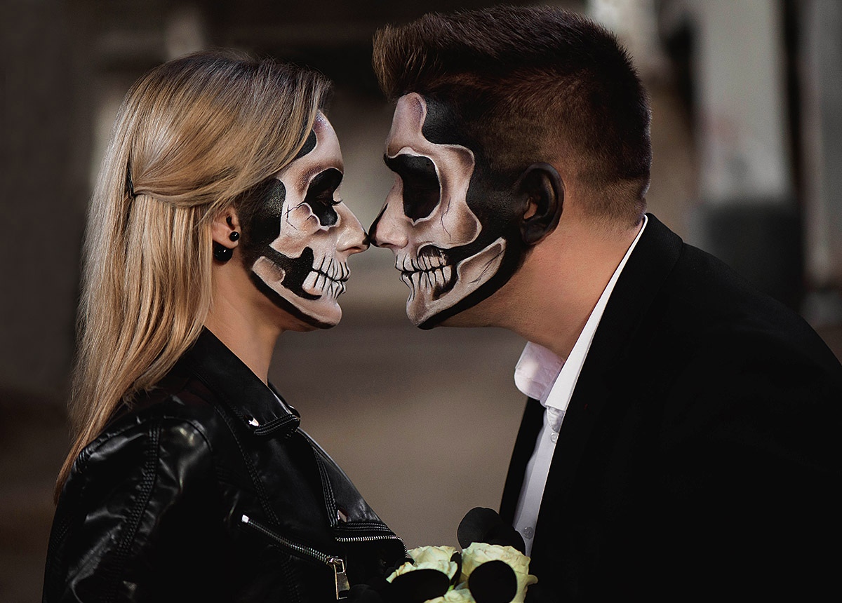 Man and woman with painted masquerade faces look at each other Man and woman with painted masquerade faces look at each other