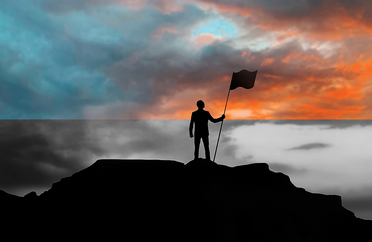 Image of a man on top of a mountain with a flag