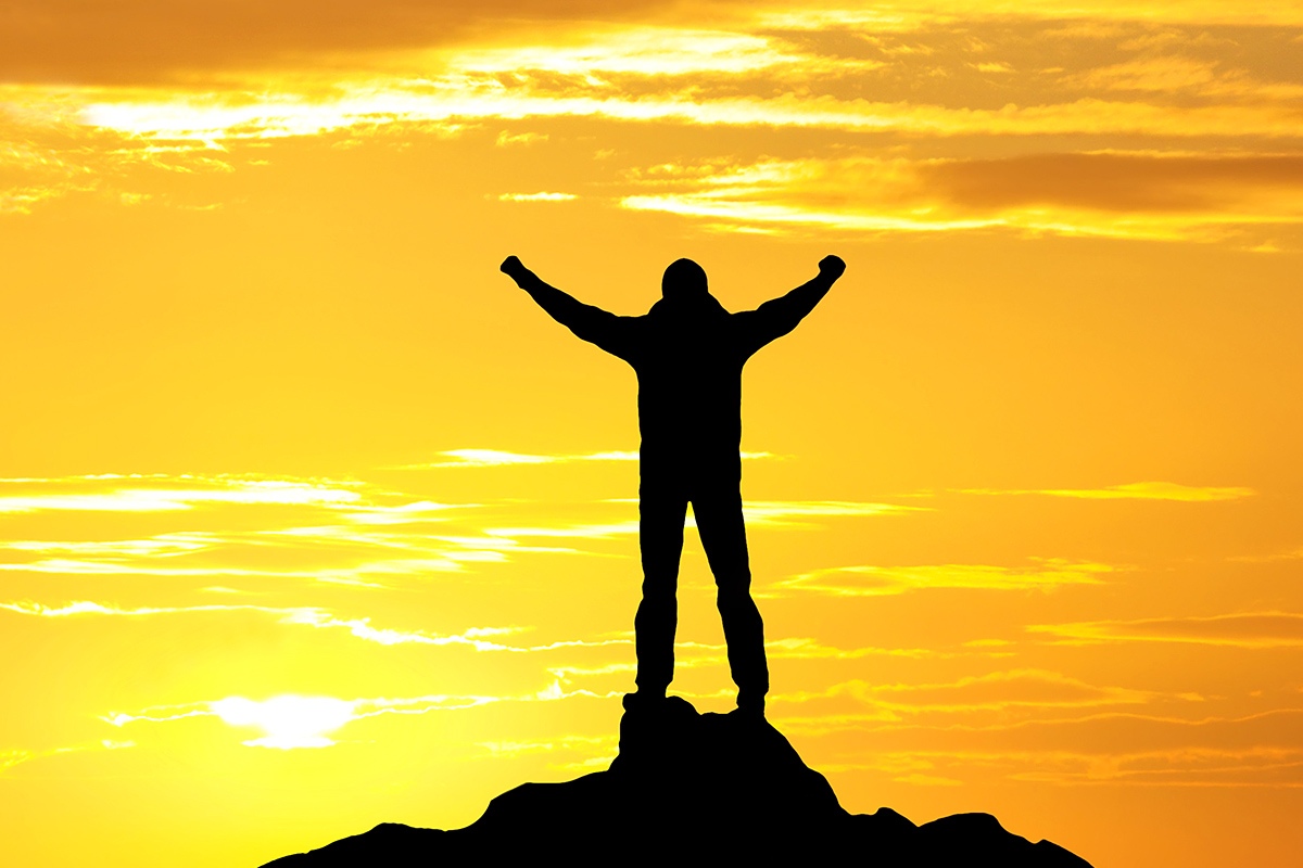 Image of a man standing on a mountain at the time of sunset