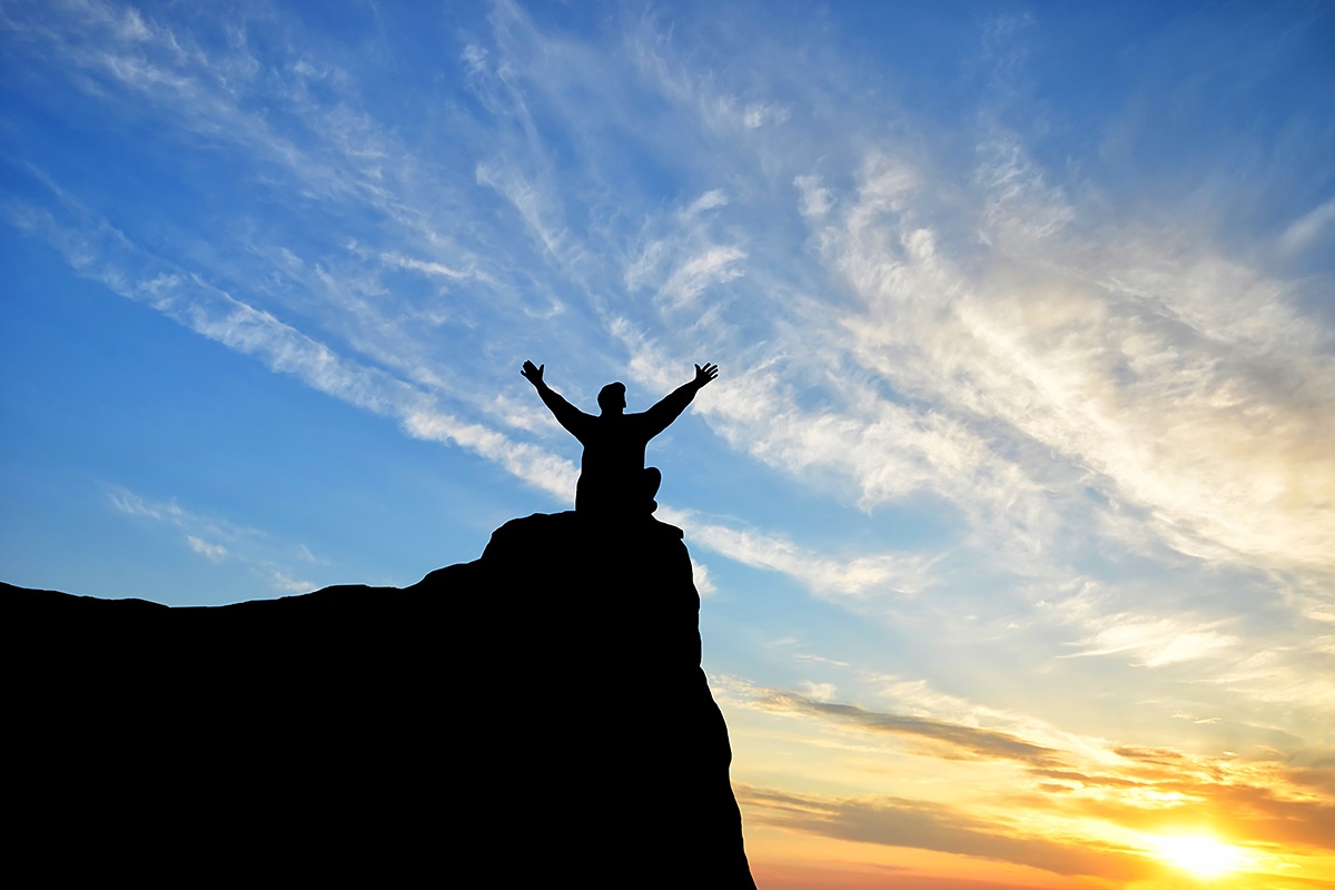 Image of a man sitting on a mountain and looking at the sky