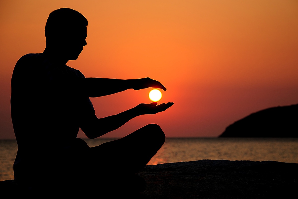 Man sits alone on the seashore during sunset Man sits alone on the seashore during sunset