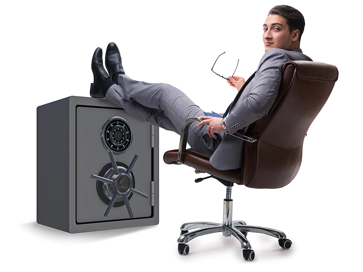 Successful business man sitting near his safe
