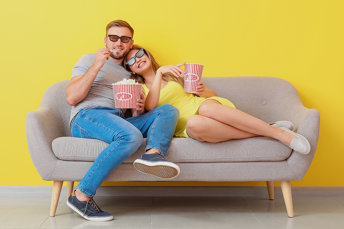 Happy couple together sitting on the sofa and watching TV