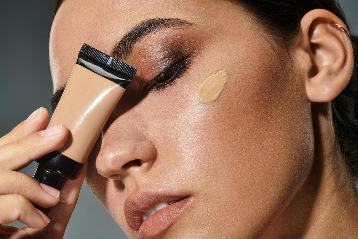 A close-up demonstration of liquid foundation application using a professional brush applicator.