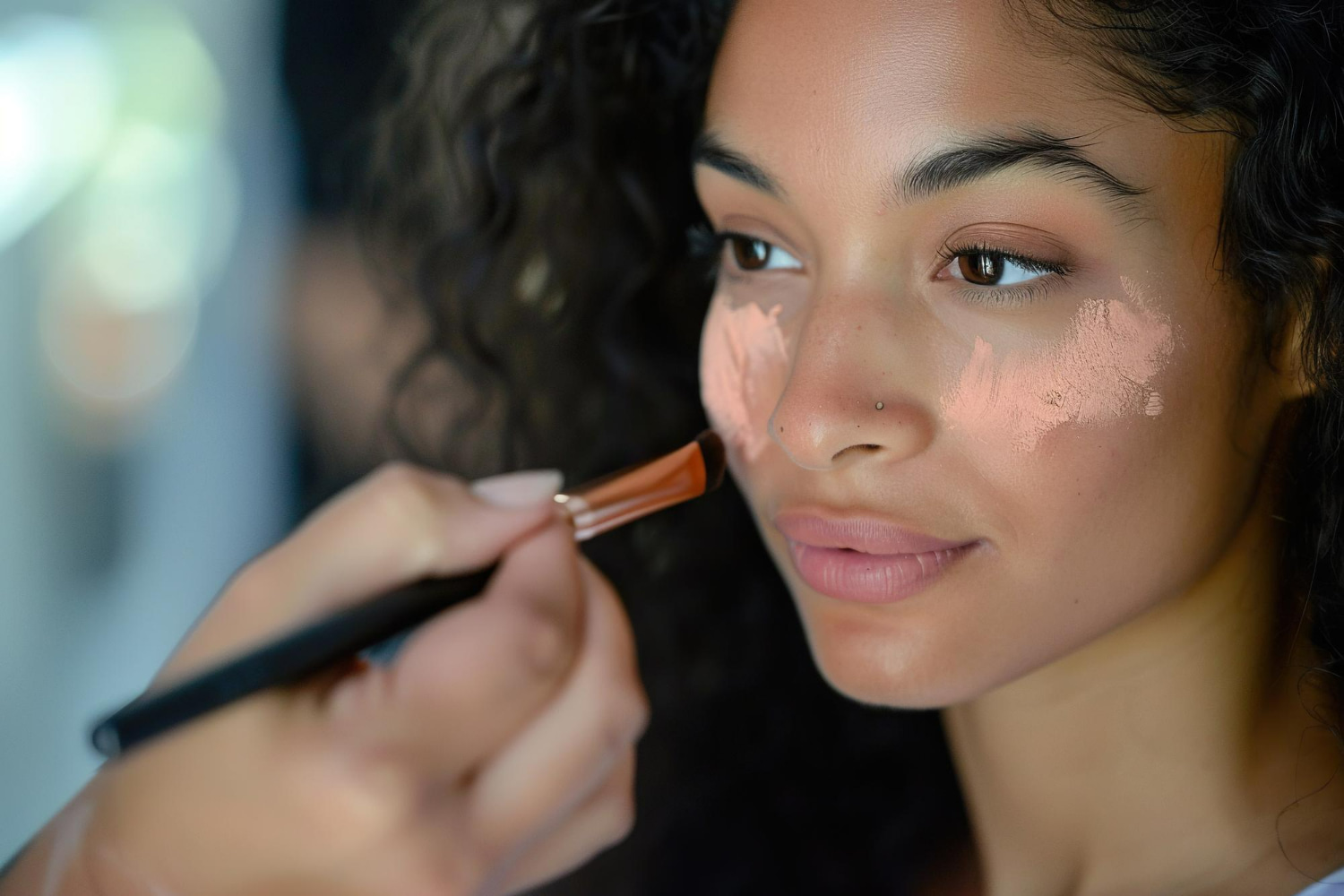 A skilled makeup artist applies expertly-blended contour using a professional angled brush to enhance facial features.