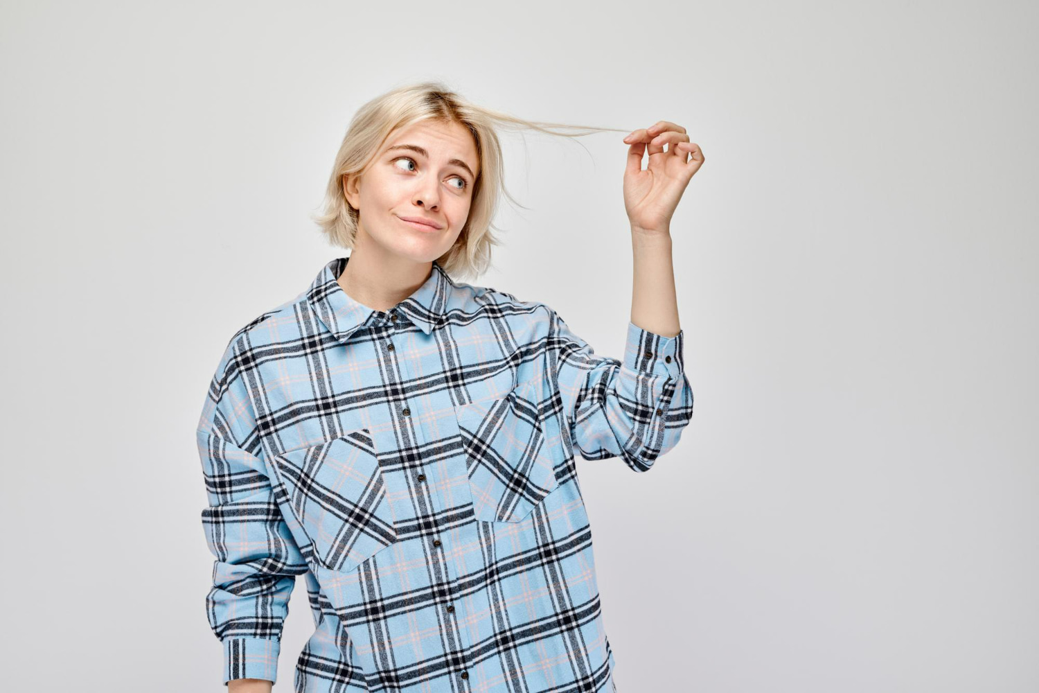 This charming portrait captures a candid moment of playful contemplation, featuring a young woman with platinum blonde hair styled in a chic, modern cut.