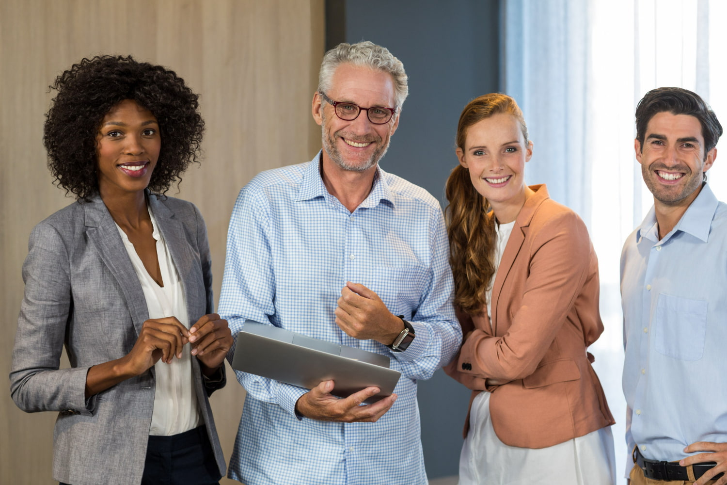 This professional stock image captures a modern, diverse team of four business professionals in a contemporary office environment.