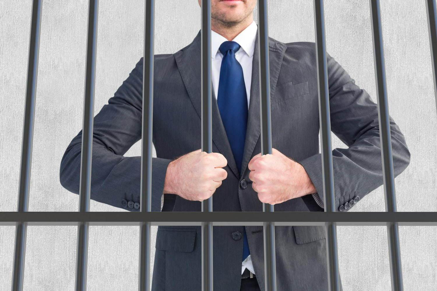 A striking photograph of a professional businessman in a charcoal suit and blue tie gripping metal prison bars.