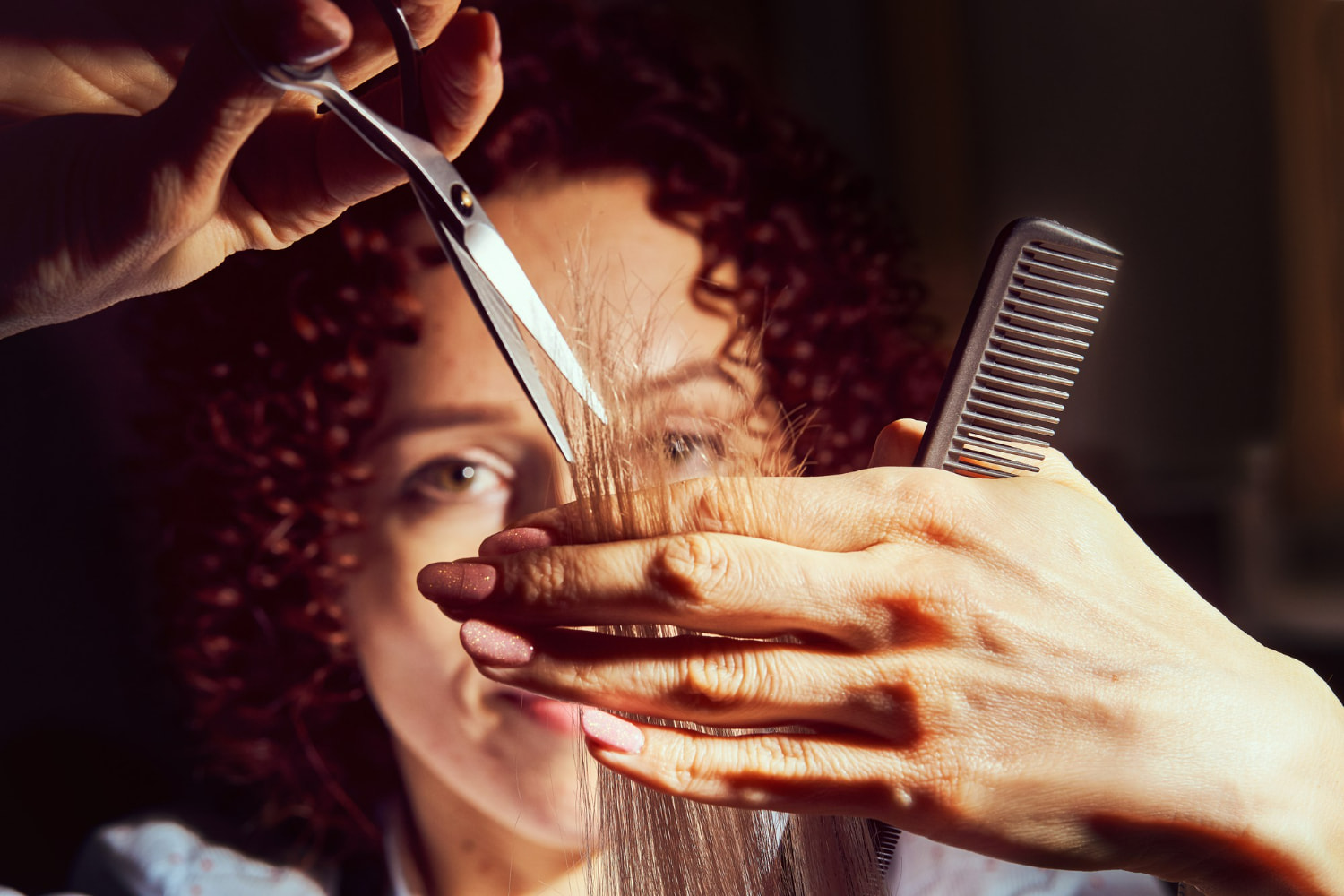 A beautifully lit, intimate portrait of a hairstylist actively working with a client.