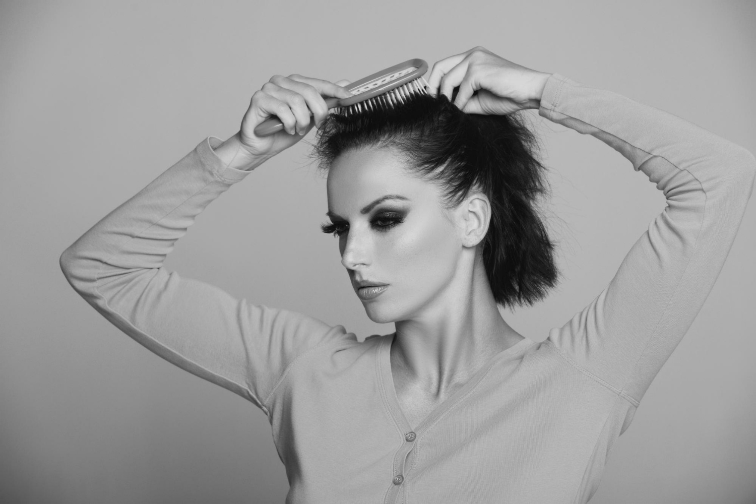 This striking black and white portrait captures an intimate moment of personal grooming elevated to an art form.